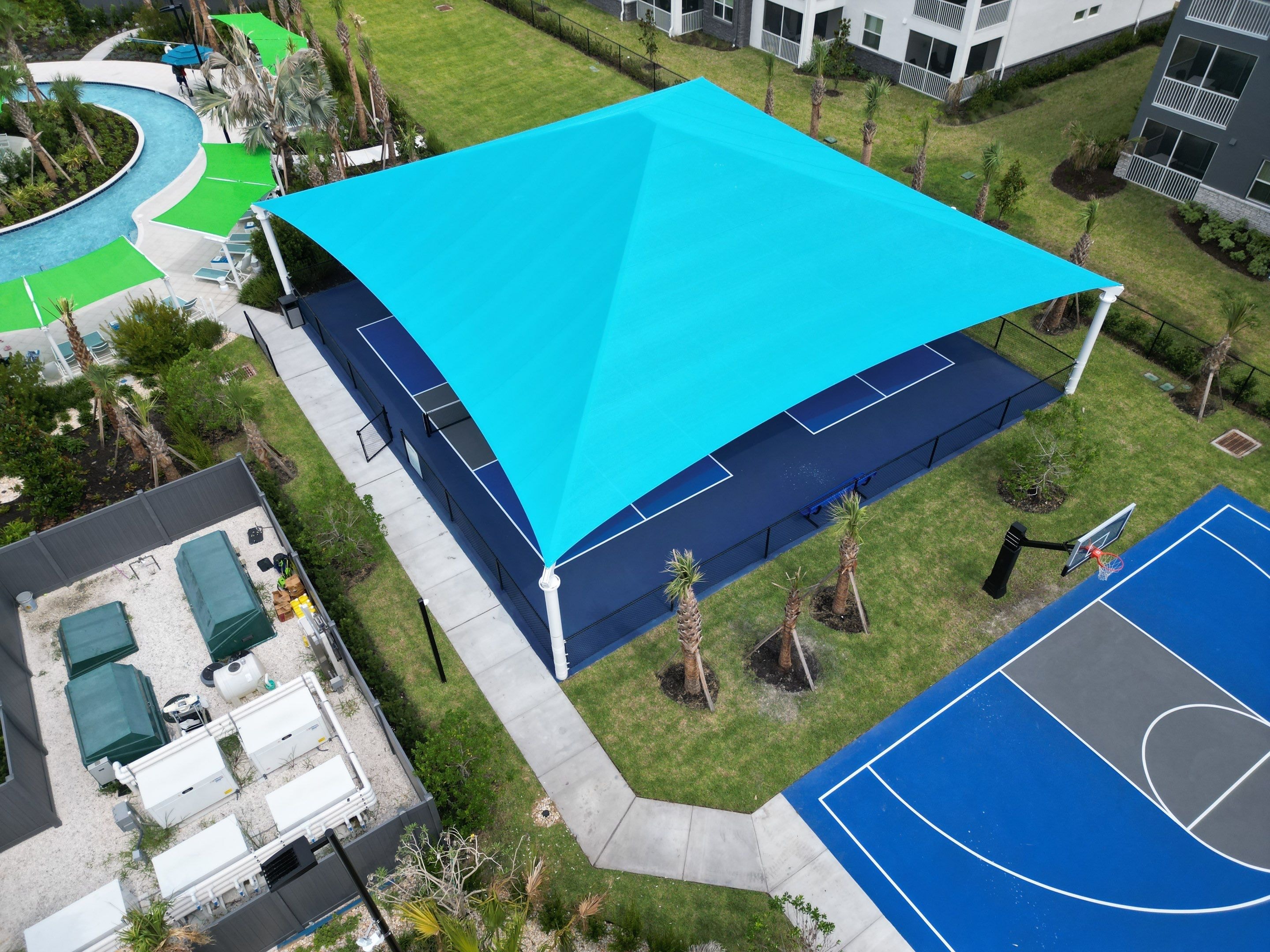 Aerial view of turquoise shade sail over resort pickleball court